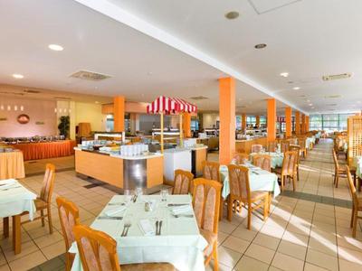 Restaurante de hotel amplio y luminoso con mesas puestas y sillas de madera.