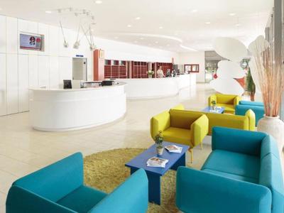 Moderna recepción de hotel con zona de asientos coloridos y mostrador blanco.