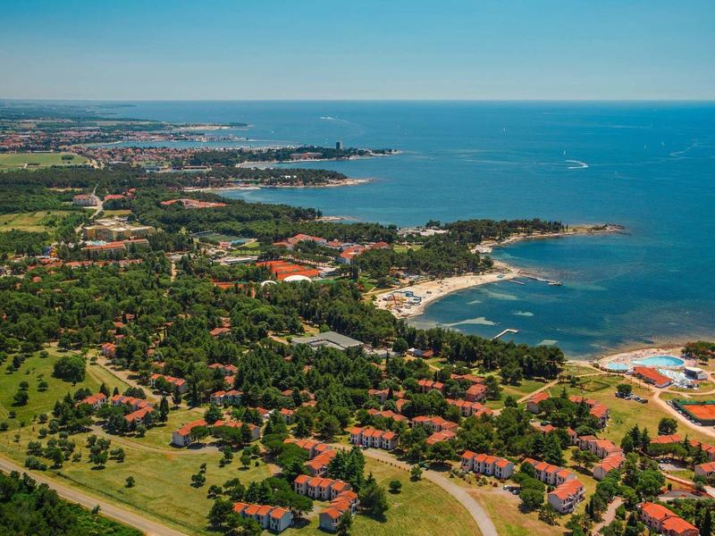 Vista aerea di una città costiera con spiagge, parchi verdi e edifici vicino al mare.