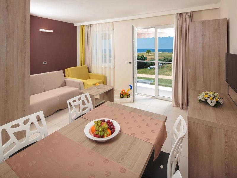 Soggiorno moderno con tavolo da pranzo, divani e vista sul mare e giardino