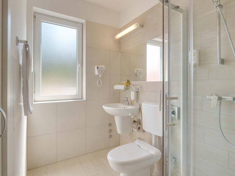 Bagno moderno e luminoso con doccia, WC e finestra per luce naturale.