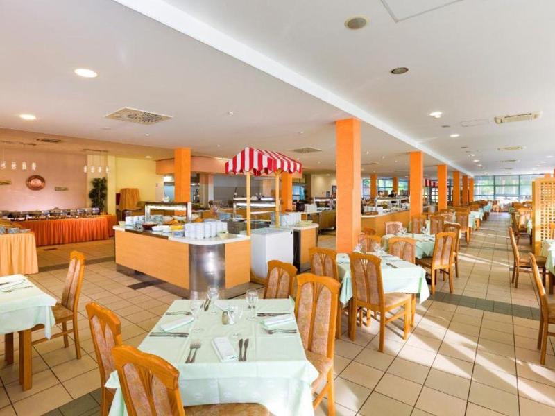 Ampia area ristorante luminosa con tavoli apparecchiati e mobili in legno.