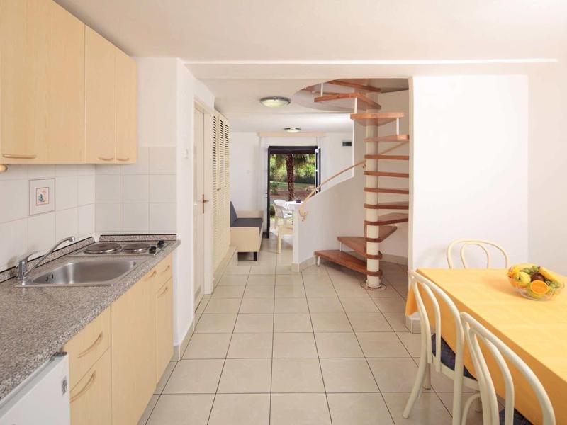 Cucina e zona pranzo moderne con scala a chiocciola e accesso aperto al soggiorno.