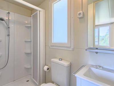 Compacte badkamer met douche, toilet, wastafel en raam.