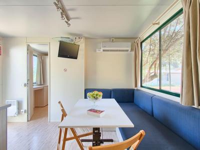 Moderner Hotel-Wohnbereich mit blauem Ecksofa, Tisch und Stühlen neben großem Fenster.