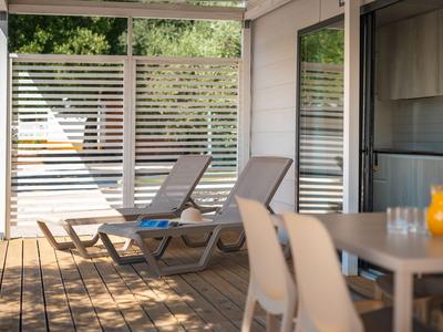 Terrasse mit Liegestühlen und Esstisch vor einem Hotelzimmer.