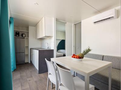 Moderner Essbereich mit weißem Tisch, Stühlen und Küchenzeile mit Kühlschrank.