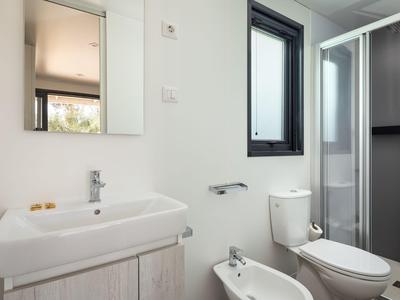 Kompaktes Badezimmer mit Waschbecken, Toilette, Bidet und Duschkabine in neutralen Tönen.