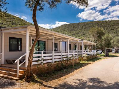 Reihe von Hotelbungalows mit Veranda in ländlicher Berglandschaft unter blauem Himmel.