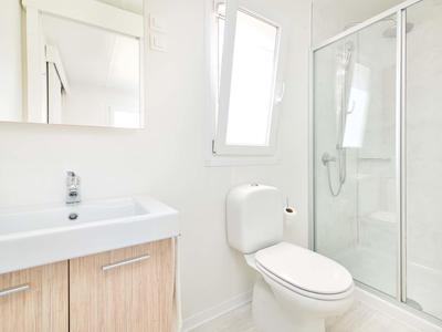 Jasna, czysta łazienka z umywalką, toaletą i szklaną kabiną prysznicową.