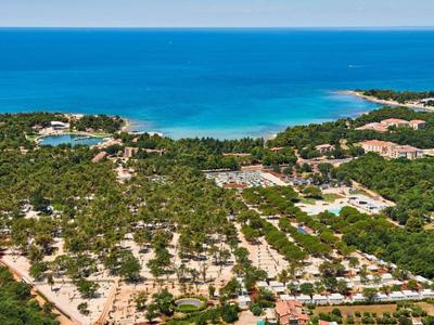 Widok z lotu ptaka na nadmorski kurort z plażą, strefami relaksu i bujną zielenią.