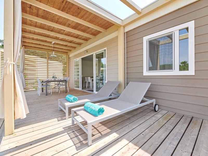 Przytulny taras z leżakami, stołem i krzesłami pod dachem, część drewnianej chaty.