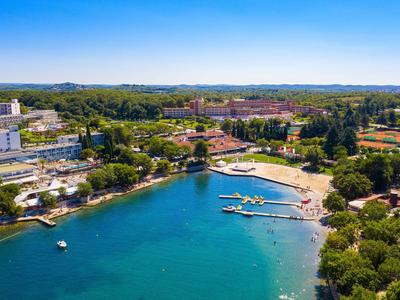 Přímořské město s hotelem, pláží a blízkými zelenými oblastmi pod jasnou oblohou