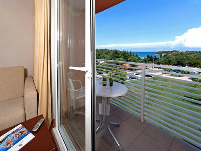 Balkon s stolem a židlemi, výhled na zelenou krajinu a moře