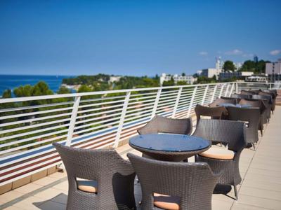 Balkon s židlemi a stoly s výhledem na moře za jasné oblohy