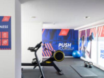 Moderní posilovna s rotopedem, gymnastickým míčem a motivačními plakáty na zdi