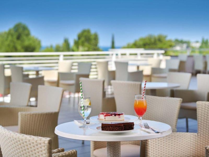 Prázdná kavárna s stolky, židlemi a dvěma nápoji na stole venku.