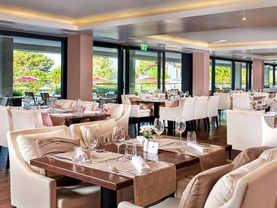 Jasna i nowoczesna restauracja z dużymi oknami i elegancko nakrytymi stołami.