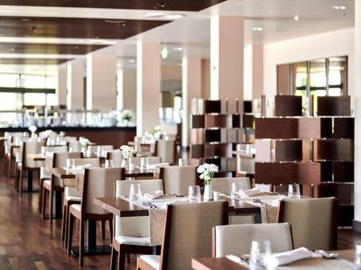 Restaurant élégant et moderne avec rangées de tables, chaises confortables et décor discret.