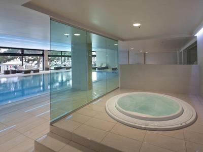 Espace intérieur moderne avec jacuzzi et grande piscine attenante.