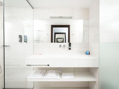 Salle de bain lumineuse avec lavabo blanc, miroir et douche moderne.