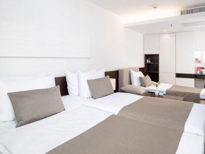 Chambre d'hôtel moderne avec deux grands lits, literie beige et décoration minimaliste.