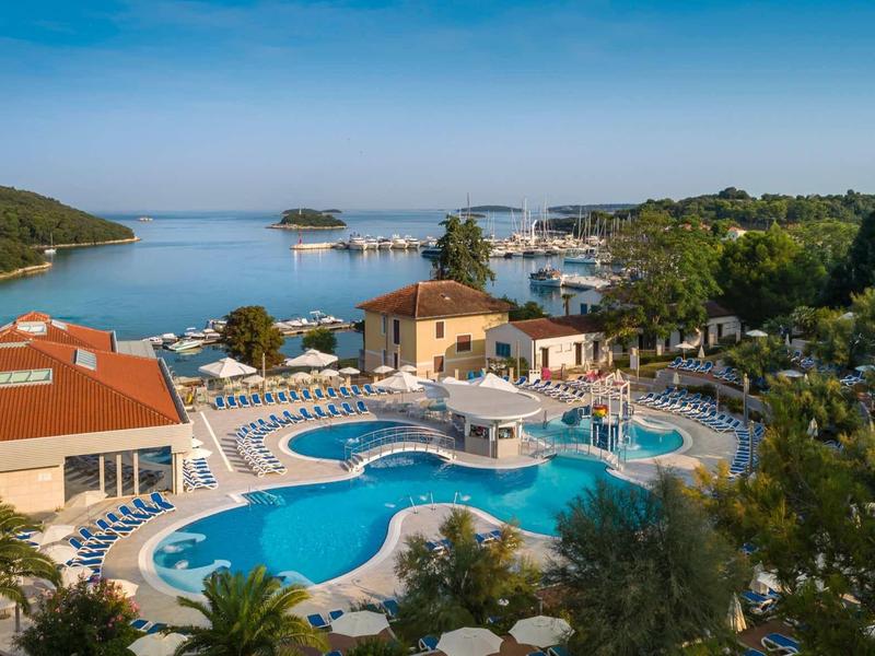 Station balnéaire de luxe avec plusieurs piscines, terrasses ensoleillées et vue sur la mer.