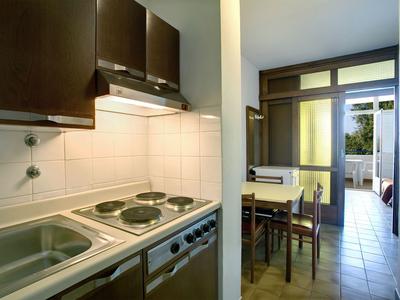 Cocina moderna con estufa y fregadero en un apartamento con vista al balcón.