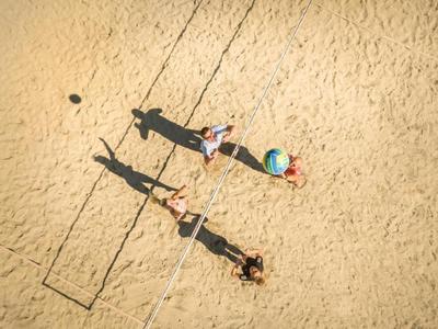 Trois personnes se détendent sur le sable à côté de l'ombre d'un cadre rectangulaire.