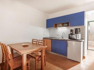 Petite cuisine avec armoire bleue, table à manger et chaises dans une pièce lumineuse