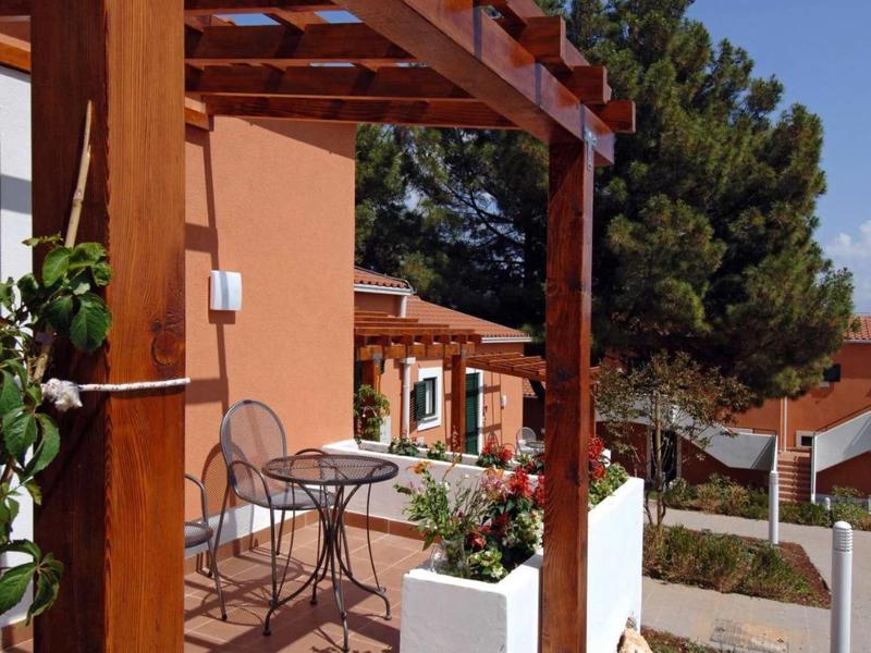 Taras z stołem i krzesłami przy pomarańczowym domu z drzewami w tle