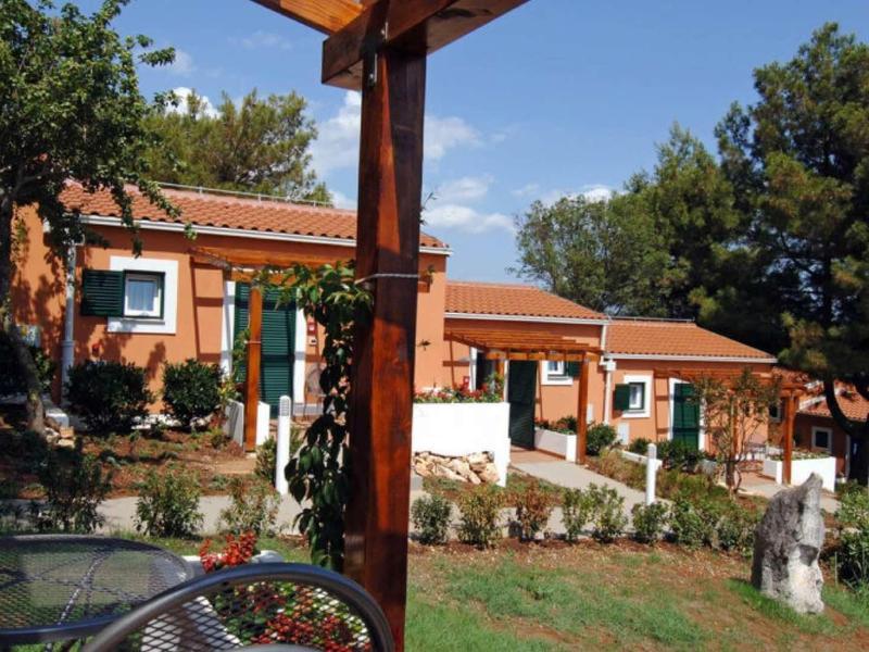 Osiedle z terakotowymi budynkami i zielonymi ogrodami pod niebieskim niebem.