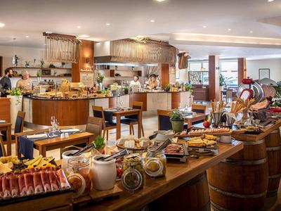 Bufet s různorodým jídlem a nápoji v elegantní restauraci s dřevěným nábytkem.