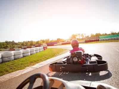 Mensen racen met karts op een racebaan in het zonlicht.
