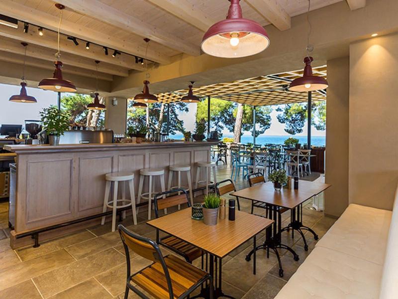 Otevřená restaurace s dřevěným nábytkem a výhledem na terasu a vodu