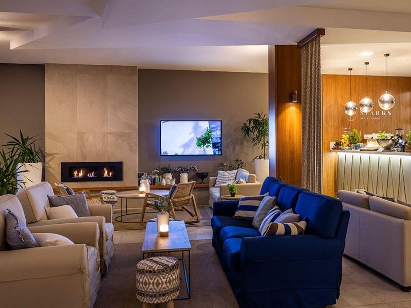 Moderní hotelový salonek s pohodlnými pohovkami, krbem a stylovým osvětlením.