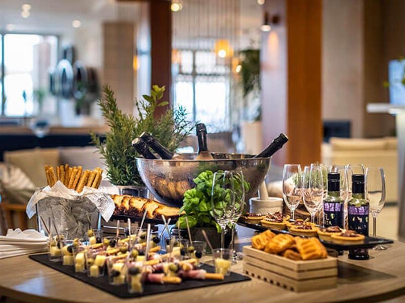 Stylový bufetový stůl s občerstvením, čerstvými bylinkami a nápoji v moderní restauraci.