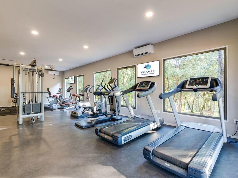 Palestra moderna con tapis roulant, biciclette e attrezzi in una stanza luminosa.