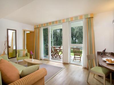 Světý obývací pokoj s pohovkami a přístupem na terasu s výhledem na zahradu.