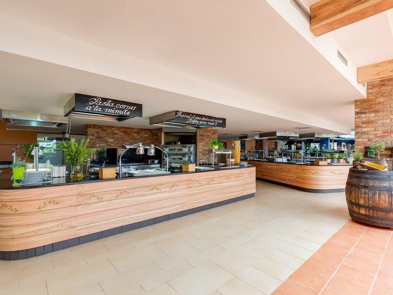 Moderní bufetový pult s dřevěným čelem a různými jídelními možnostmi v hotelové restauraci.