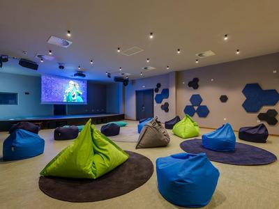Salle de loisirs moderne avec poufs colorés et projecteur dans un hôtel.