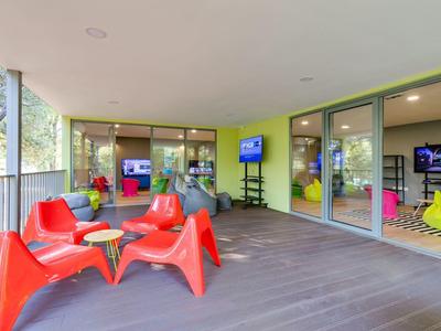 Terrasse couverte avec des chaises rouges et des murs en verre à côté d'une chambre d'hôtel
