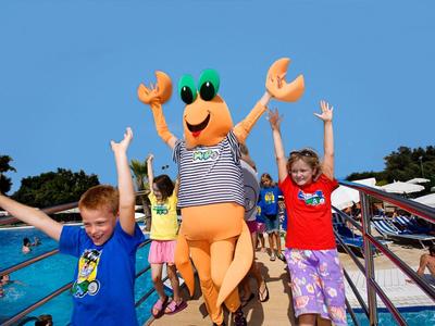Des enfants jouent près de la piscine avec une mascotte crabe, s'amusant pendant les vacances.