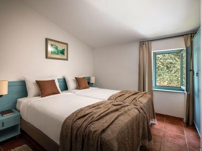 Pohodlný hotelový pokoj se dvěma postelemi, hnědou přikrývkou a výhledem z okna.