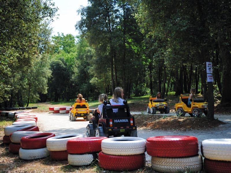 Personne conduisant sur une piste de karting entourée d'arbres et de pneus rouge-blancs