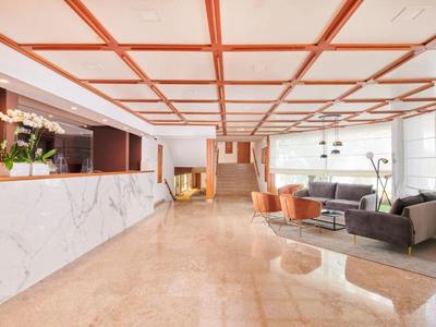 Hall d'hôtel lumineux avec réception en marbre et espaces de détente modernes.