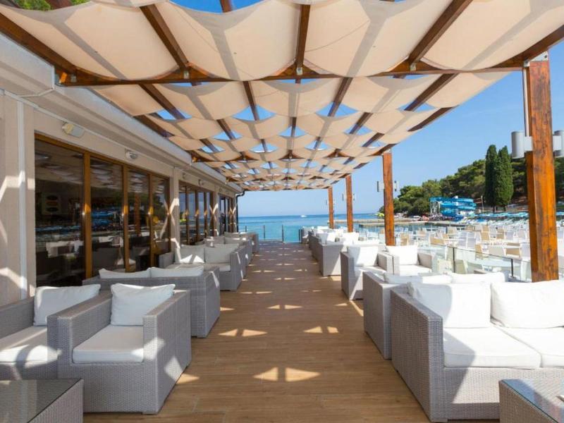 Terrasse couverte avec fauteuils blancs et vue sur la mer.