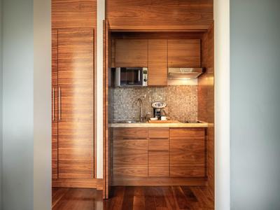 Kleine Küchenecke aus Holz mit Mikrowelle und Kaffeemaschine in einem Hotelzimmer.