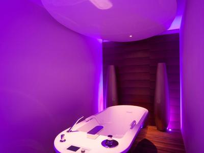Moderner Whirlpool mit lila Beleuchtung in einem luxuriösen Spa-Bereich eines Hotels.