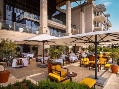Área exterior de restaurante con mesas, sillas y grandes sombrillas en un ambiente acogedor.